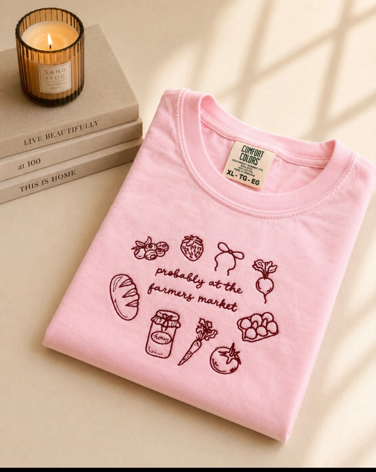 Pink Comfort Colors embroidered t-shirt featuring “Probably At The Farmers Market” design with market-inspired icons including strawberries, bread, carrots, honey, and vegetables.