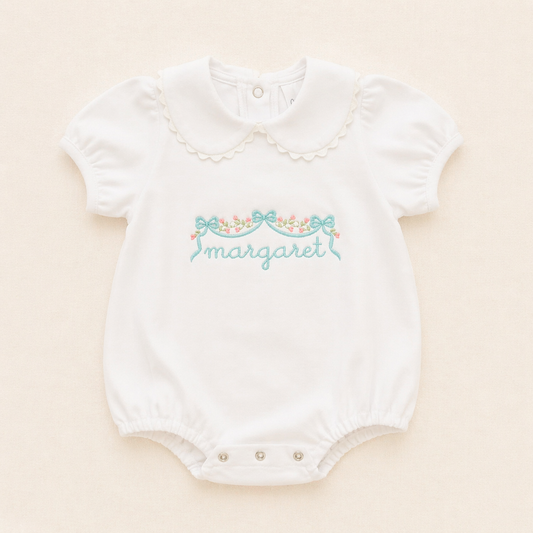 Personalized white baby bubble romper with scalloped collar on soft ivory background