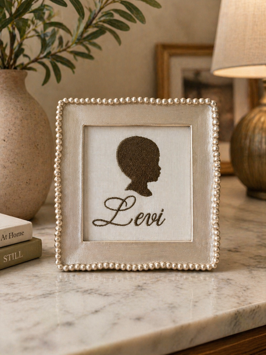 Framed silhouette with 'Levi' on a marble surface with decorative items.