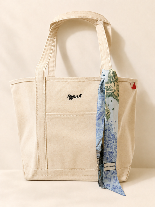 Large cream canvas tote embroidered with personalization and styled with a blue patterned twilly scarf.