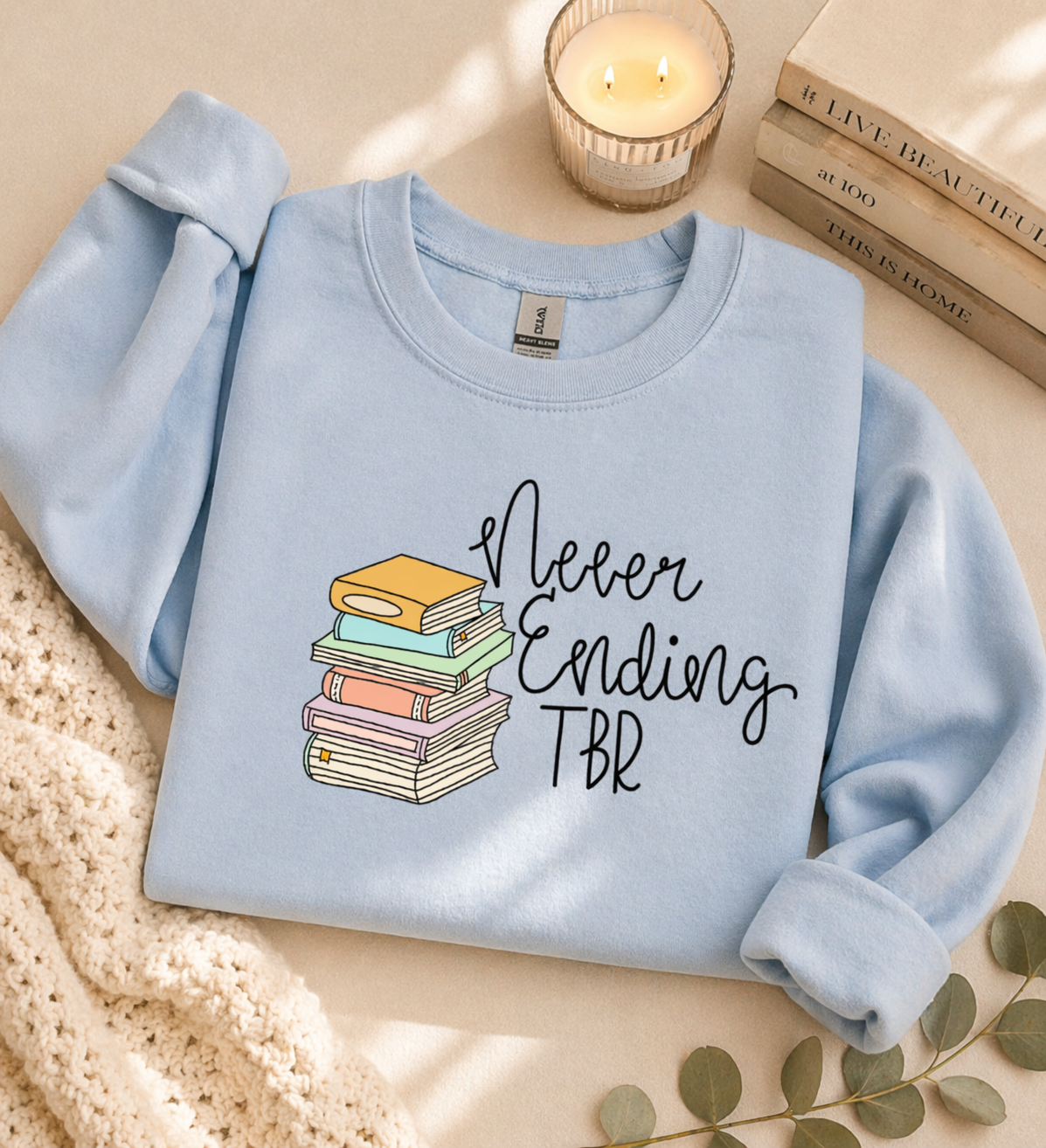 Cozy book lover sweatshirt in sky blue with never ending TBR design styled in neutral aesthetic flatlay