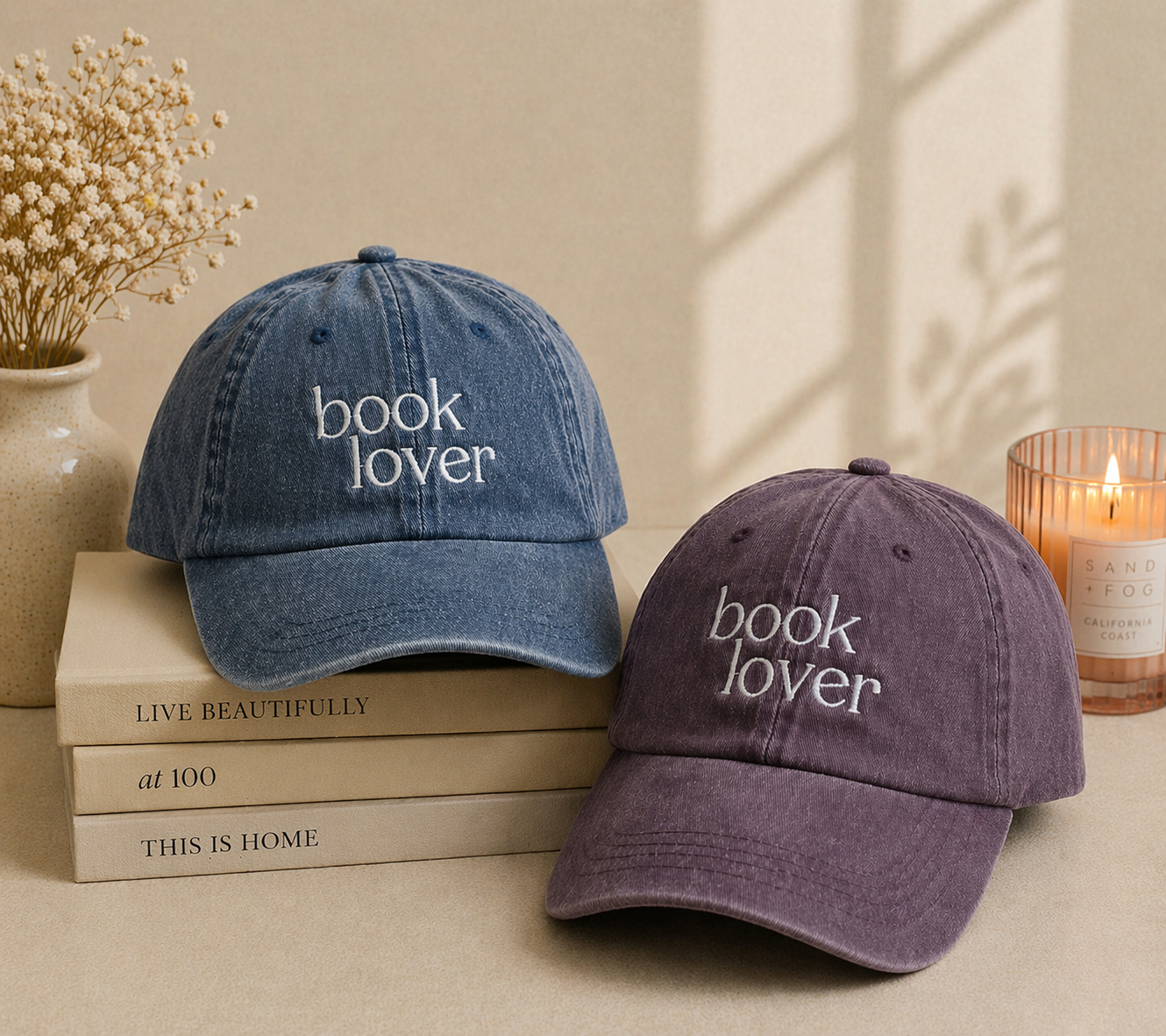 Two 'book lover' hats on books with a candle and vase in the background