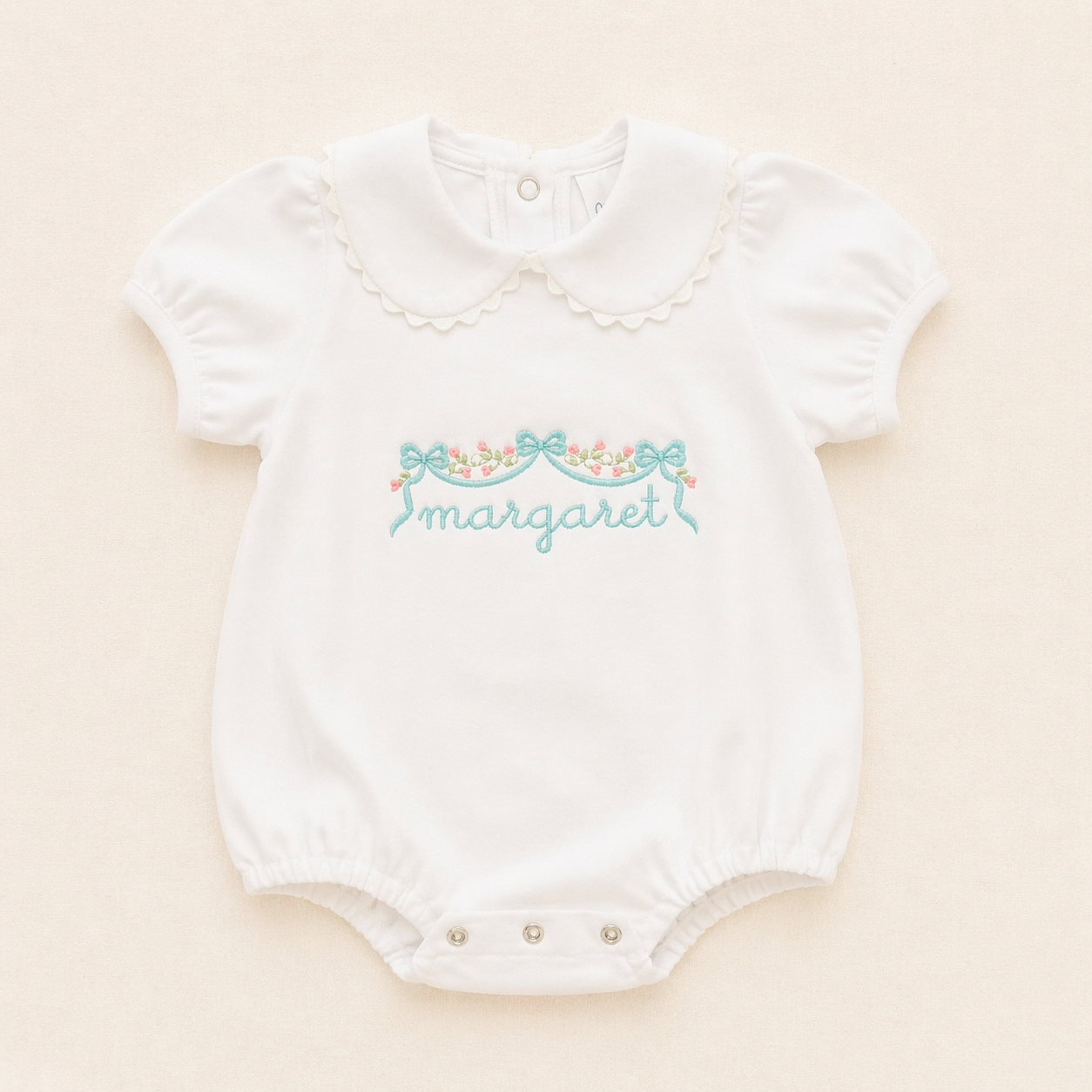 Personalized white baby bubble romper with scalloped collar on soft ivory background