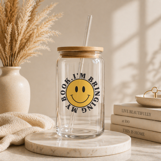 glass iced coffee cup with smiley face and bringing my book text held in hand with colorful bookstore background