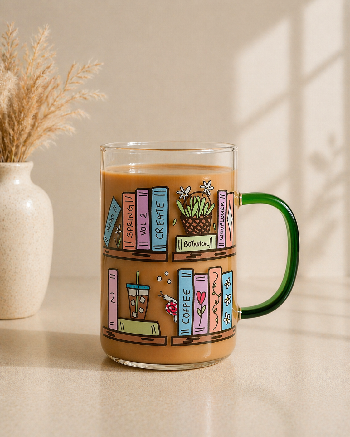 clear glass coffee mug with illustrated bookshelf and books design being held in hand with candle and books in background