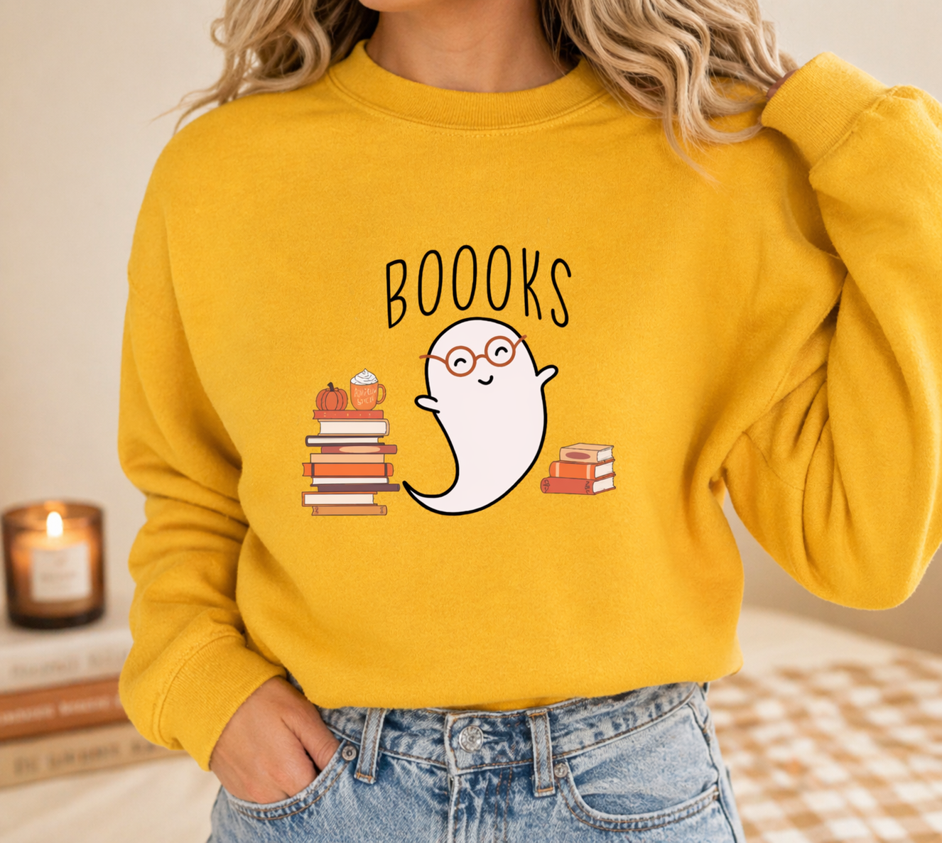 Lightweight mustard sweatshirt with cute ghost reading books design, styled in cozy neutral flatlay with books and candle