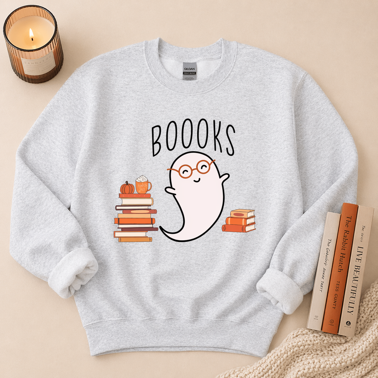 Gray sweatshirt with a ghost and book design labeled 'BOOOKS' on a beige background.