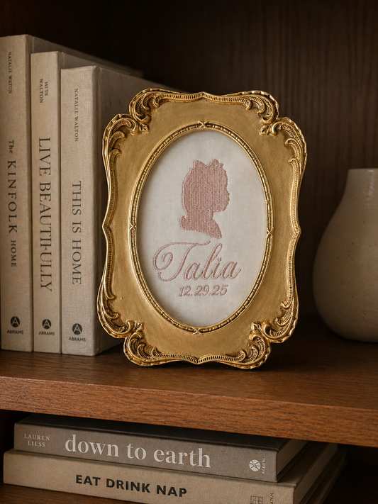 Decorative gold frame with a silhouette and text on a shelf with books and a vase.