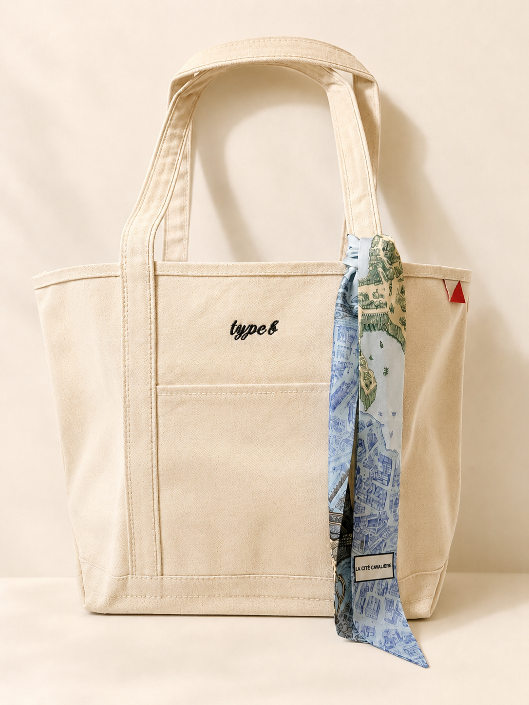 Large cream canvas tote embroidered with personalization and styled with a blue patterned twilly scarf.