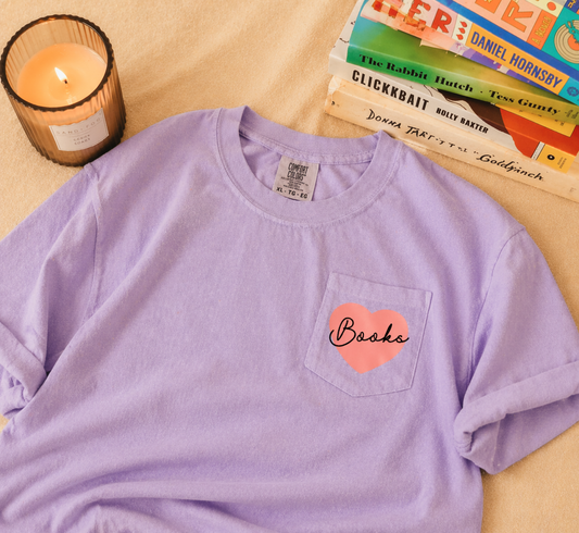 lavender t-shirts with small heart graphic reading “Books” styled with candle and stacked books